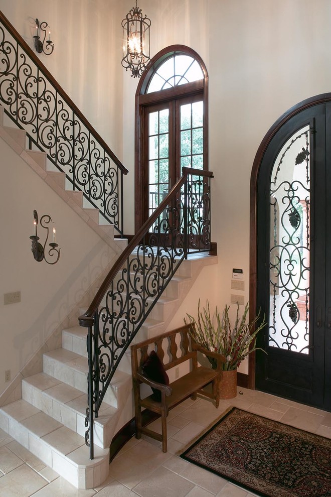 На фото: большая угловая лестница в средиземноморском стиле с ступенями из плитки, подступенками из плитки и металлическими перилами