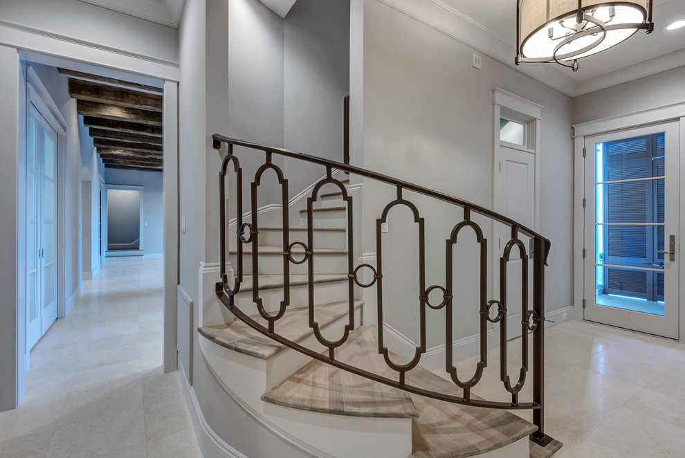 Diseño de escalera curva clásica de tamaño medio con escalones de madera, contrahuellas de madera pintada y barandilla de metal