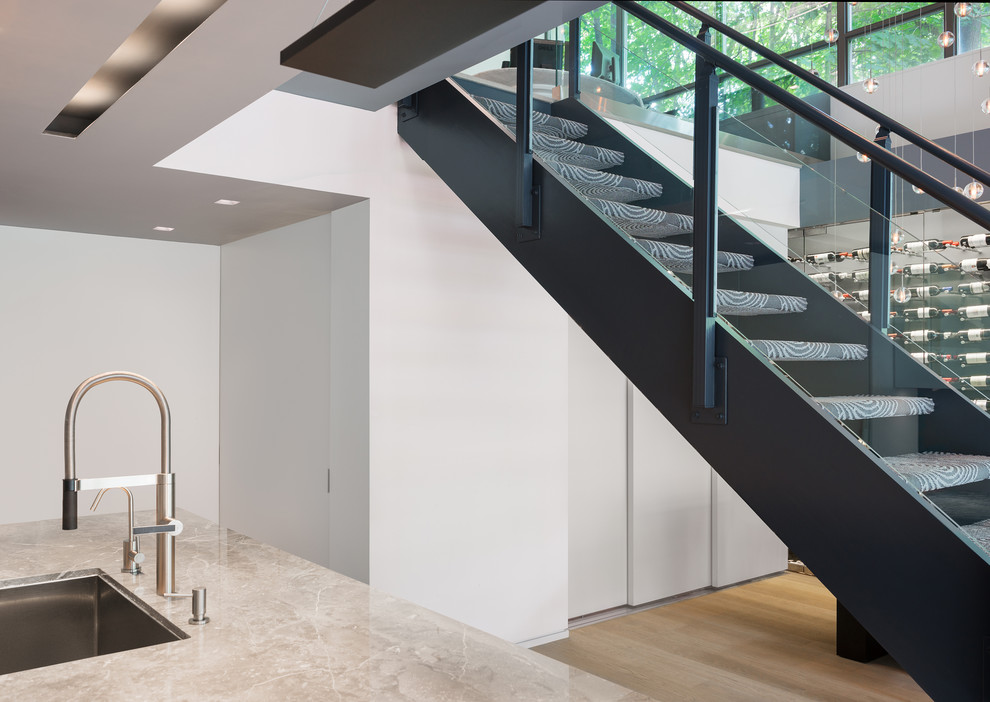 Стильный дизайн: лестница среднего размера, на больцах в современном стиле с ступенями с ковровым покрытием и стеклянными перилами без подступенок - последний тренд