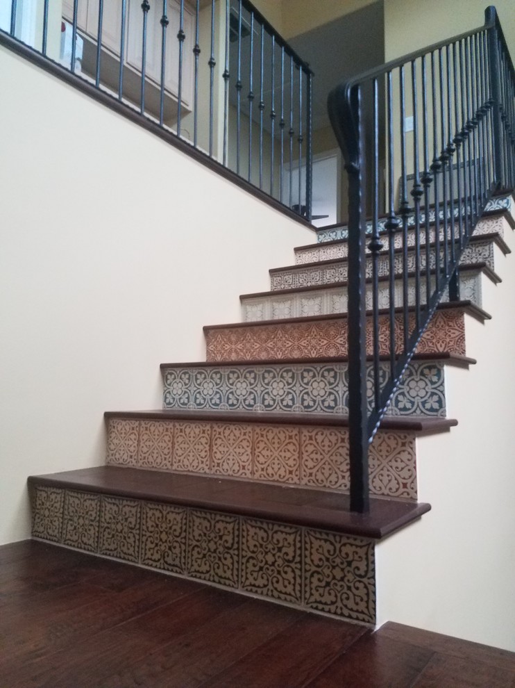 Diseño de escalera en U mediterránea de tamaño medio con escalones de madera, contrahuellas con baldosas y/o azulejos y barandilla de metal