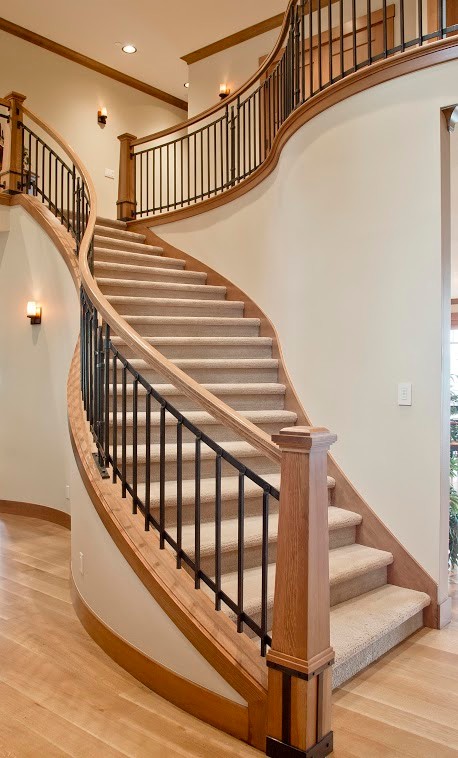 Пример оригинального дизайна: огромная изогнутая лестница в стиле кантри с ступенями с ковровым покрытием и ковровыми подступенками