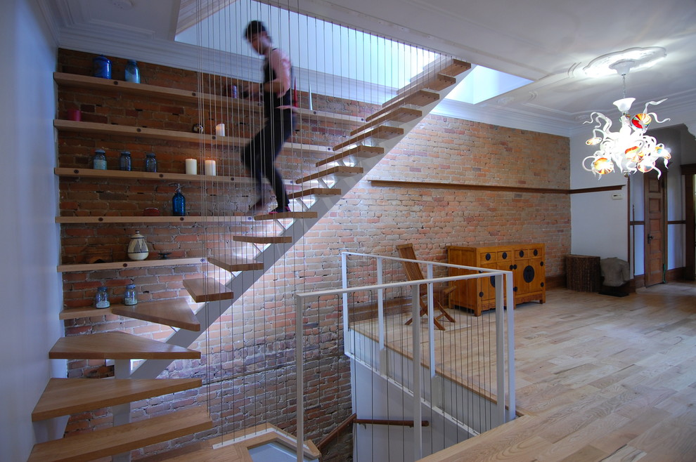 Imagen de escalera en L ecléctica de tamaño medio sin contrahuella con escalones de madera, barandilla de metal y ladrillo