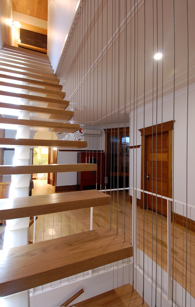 Diseño de escalera en L ecléctica sin contrahuella con escalones de madera y barandilla de metal