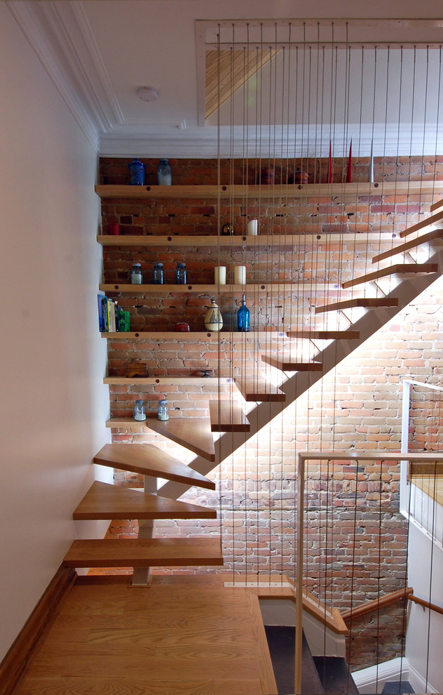 Réalisation d'un escalier sans contremarche bohème en L de taille moyenne avec des marches en bois, un garde-corps en métal et un mur en parement de brique.