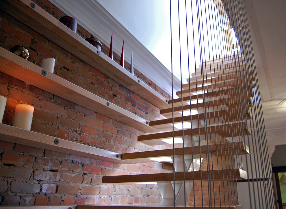 Aménagement d'un escalier sans contremarche éclectique en L de taille moyenne avec des marches en bois, un garde-corps en métal et un mur en parement de brique.