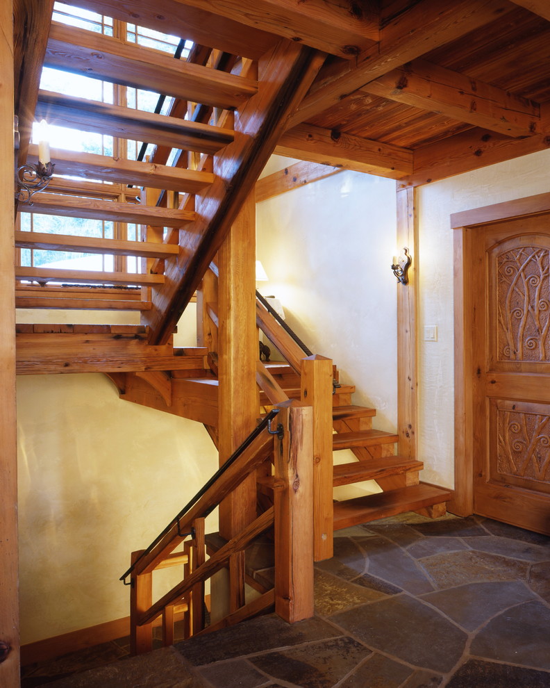 На фото: большая п-образная лестница в стиле рустика с деревянными ступенями и деревянными перилами без подступенок