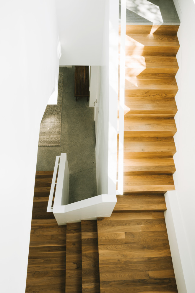 На фото: п-образная деревянная лестница среднего размера в стиле модернизм с деревянными ступенями и металлическими перилами