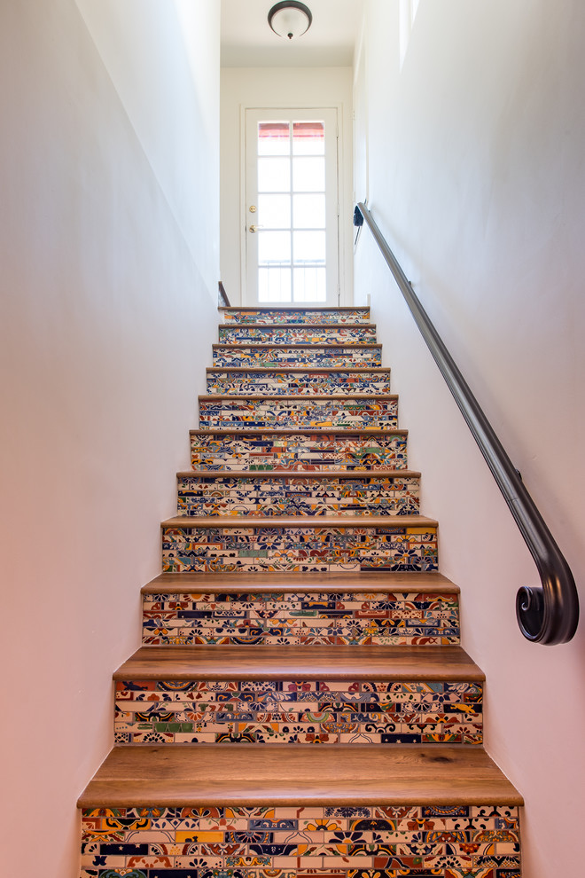 Inspiration for a large mediterranean wood straight staircase in San Diego with tiled risers and feature lighting.