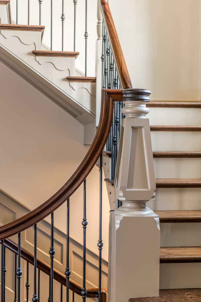 На фото: большая п-образная лестница в классическом стиле с деревянными ступенями, крашенными деревянными подступенками и металлическими перилами