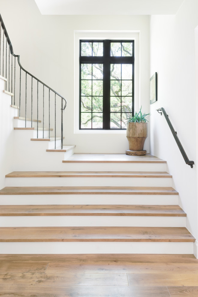 На фото: п-образная лестница в стиле неоклассика (современная классика) с деревянными ступенями, крашенными деревянными подступенками и металлическими перилами с