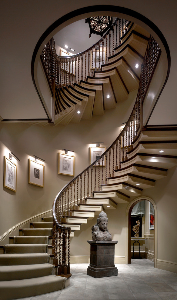 На фото: изогнутая деревянная лестница в классическом стиле с деревянными ступенями и деревянными перилами с