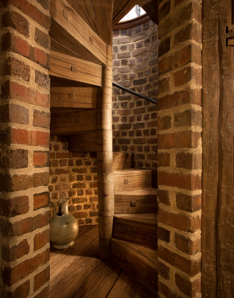 Immagine di una scala a chiocciola rustica con pedata in legno e alzata in legno