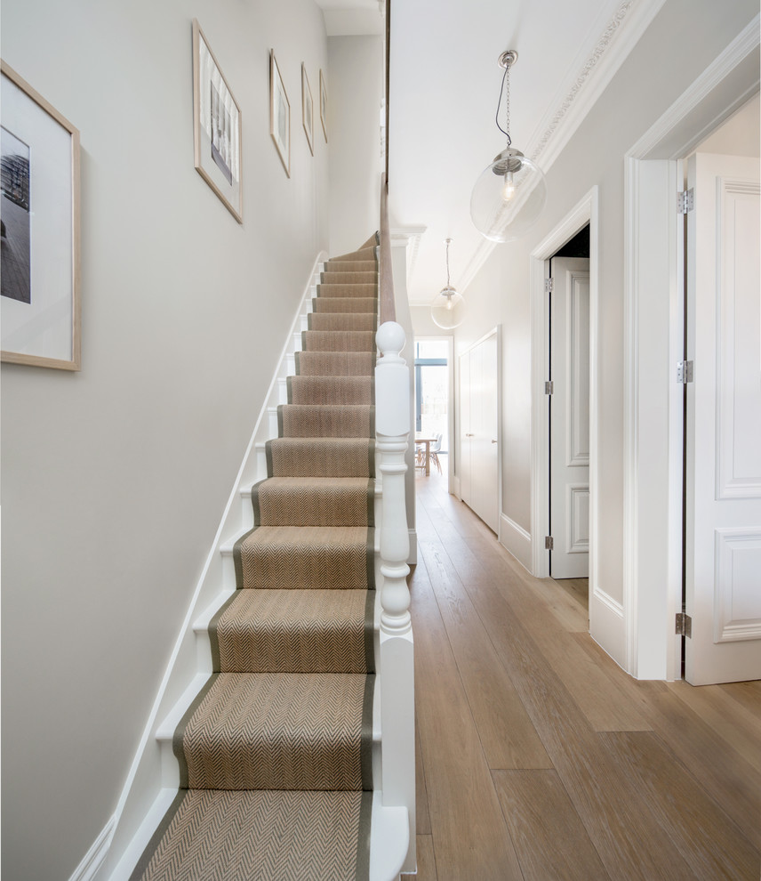 ロンドンにある中くらいなトラディショナルスタイルのおしゃれな直階段 (木材の手すり、フローリングの蹴込み板) の写真