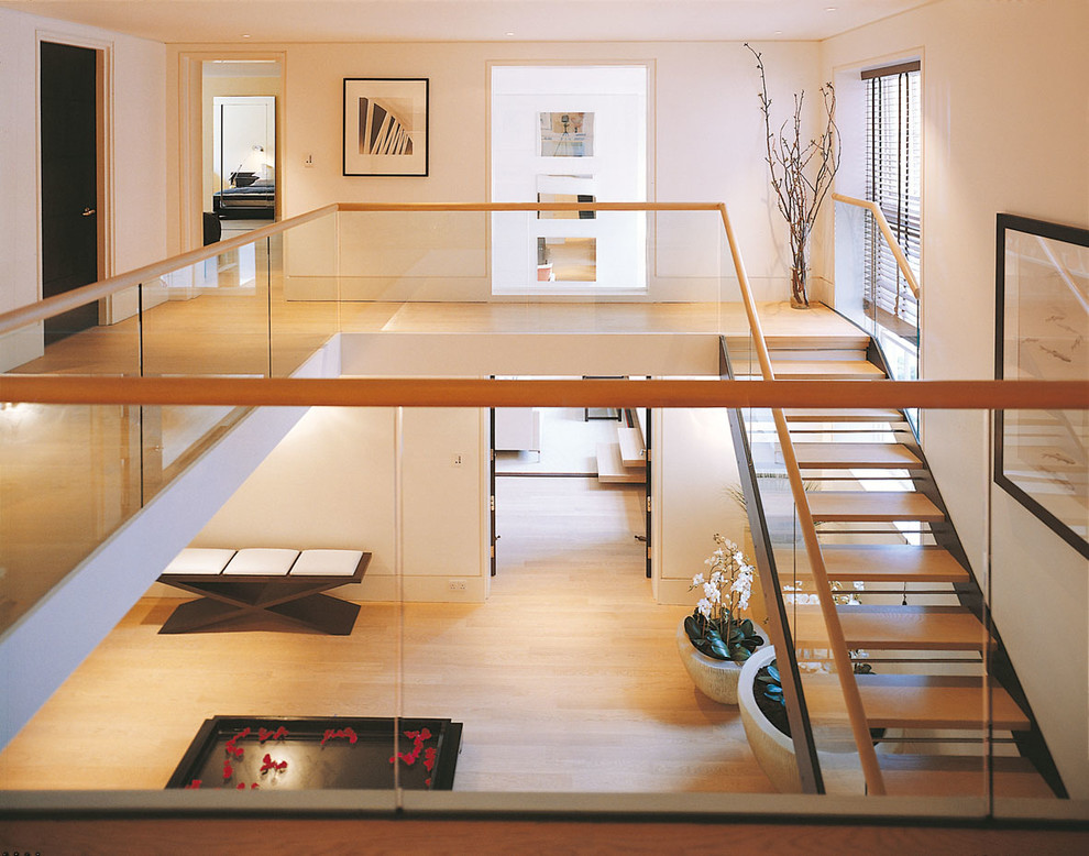 Inspiration for a transitional wooden open and glass railing staircase remodel in London