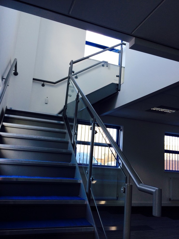 На фото: прямая лестница в современном стиле с металлическими ступенями и ковровыми подступенками с
