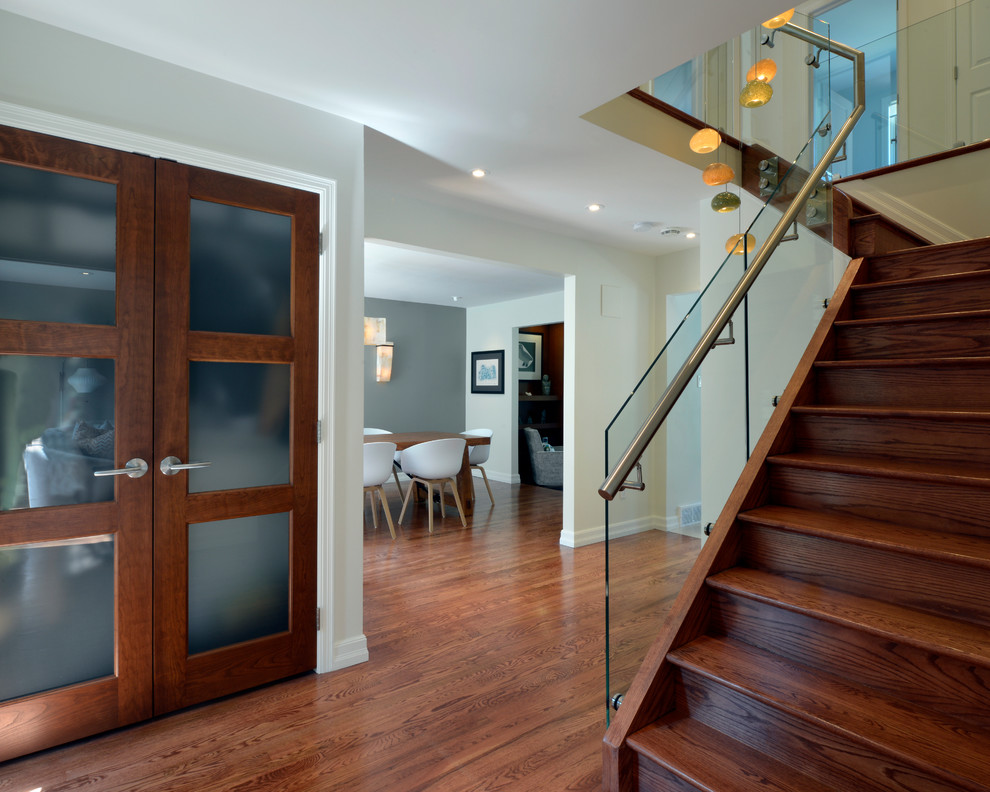 Ejemplo de escalera en L actual de tamaño medio con escalones de madera, contrahuellas de madera y barandilla de vidrio