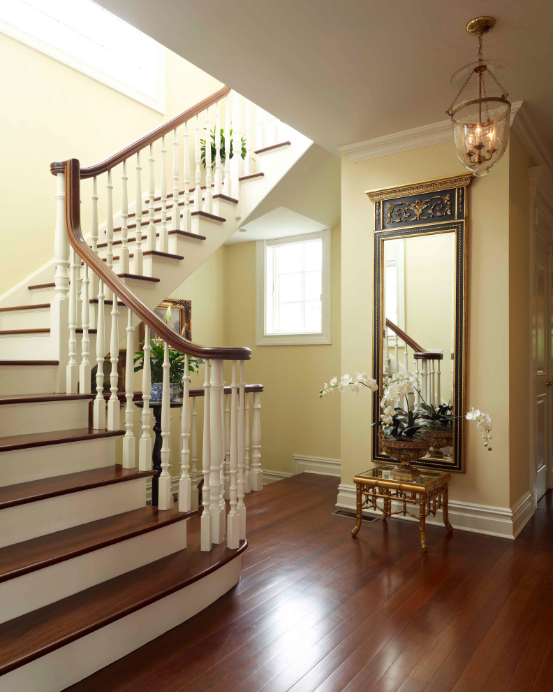 На фото: п-образная лестница в классическом стиле с деревянными ступенями, крашенными деревянными подступенками и деревянными перилами