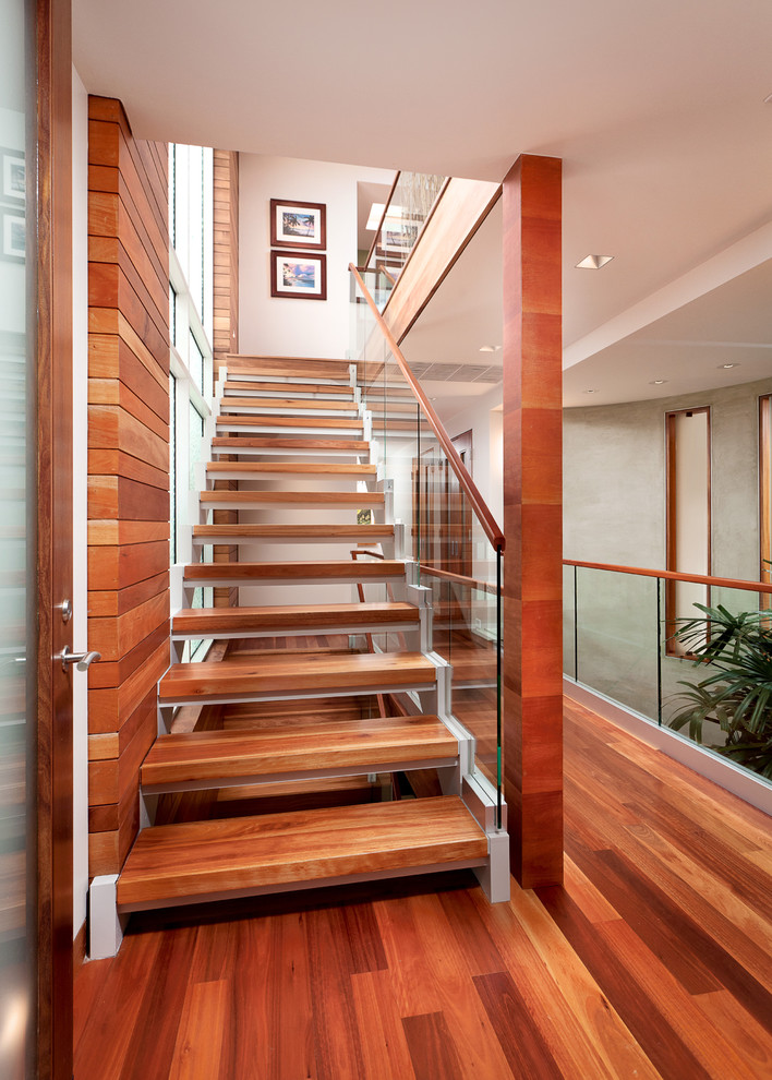 На фото: прямая лестница среднего размера в современном стиле с деревянными ступенями и стеклянными перилами без подступенок