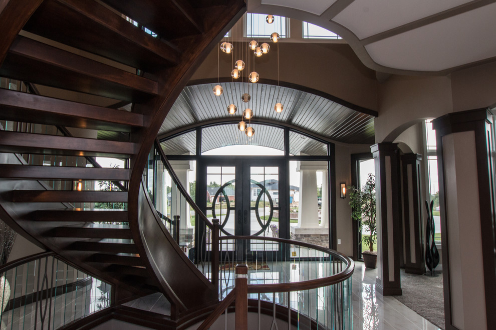 Imagen de escalera curva ecléctica grande sin contrahuella con escalones de madera y barandilla de vidrio