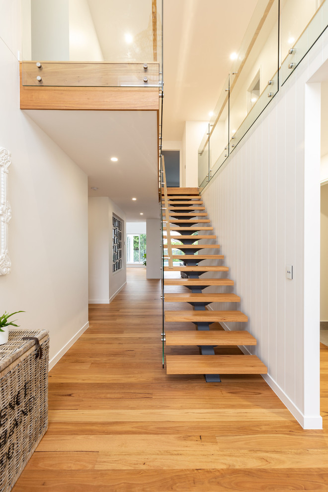 На фото: лестница на больцах, среднего размера в стиле модернизм с деревянными ступенями и стеклянными перилами без подступенок