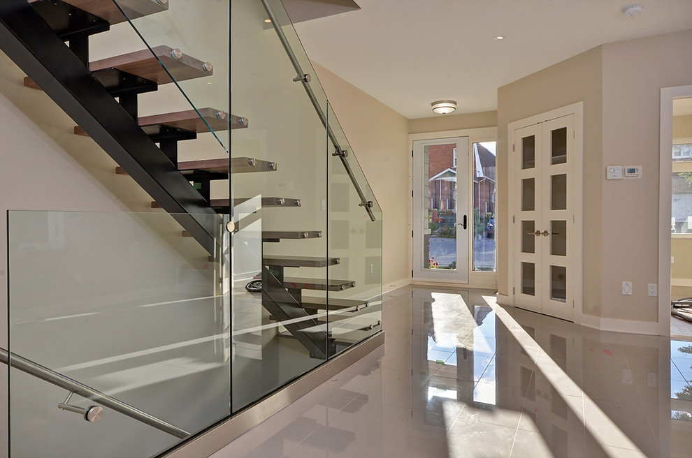 Cette image montre un grand escalier sans contremarche droit design avec des marches en bois, un garde-corps en verre et éclairage.