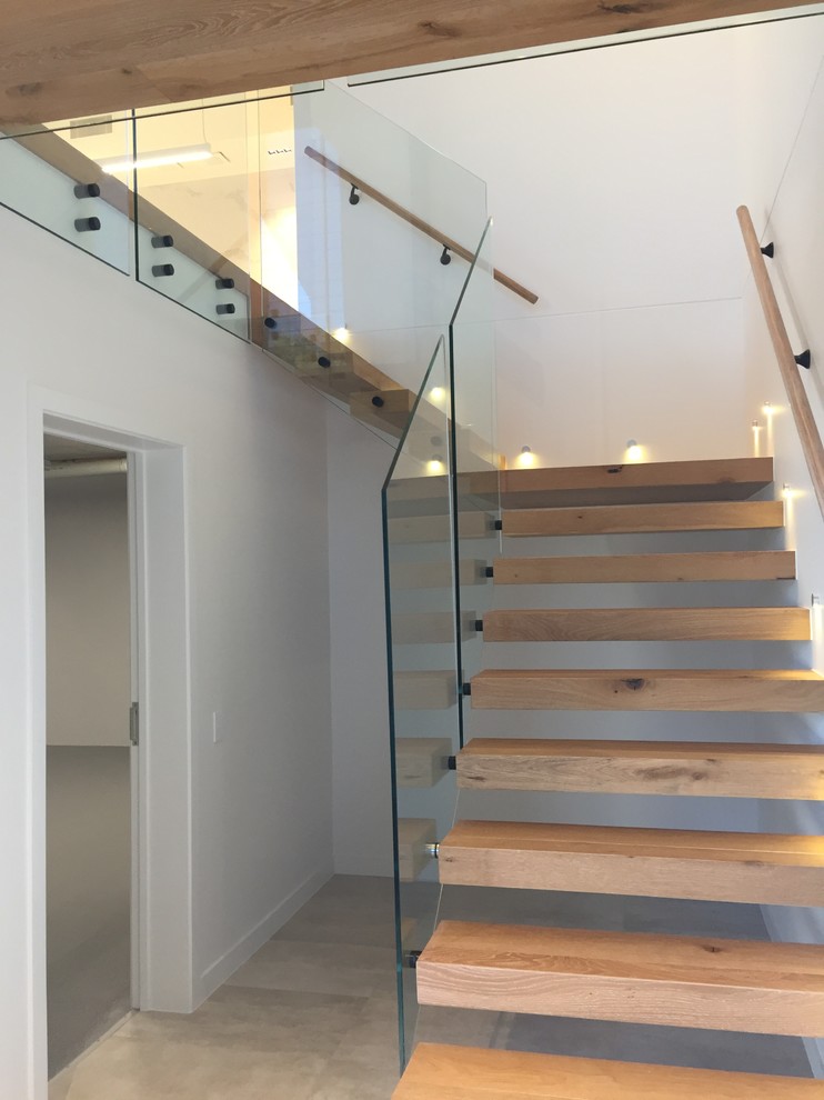 Imagen de escalera suspendida moderna de tamaño medio sin contrahuella con escalones de madera y barandilla de vidrio