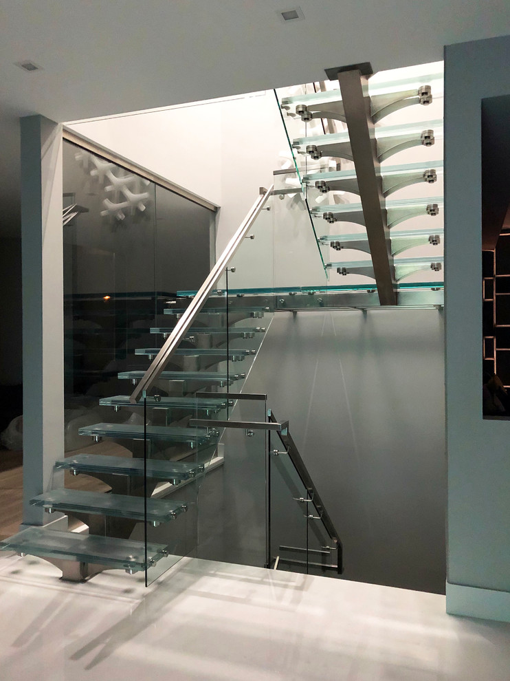 На фото: п-образная лестница среднего размера в современном стиле с стеклянными ступенями и перилами из смешанных материалов без подступенок