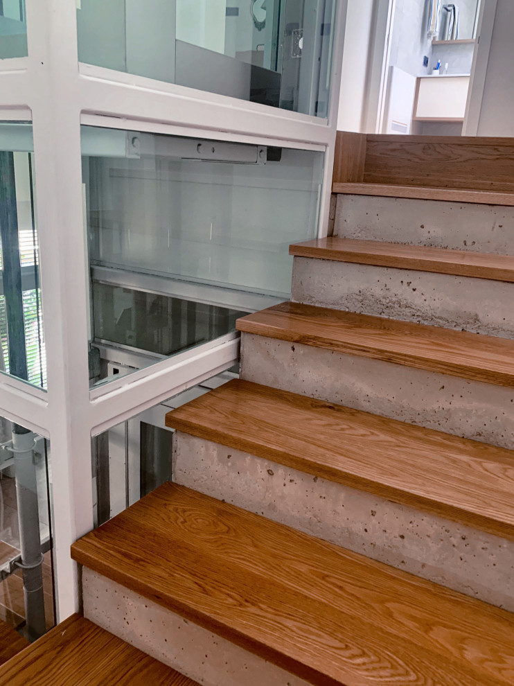 Foto på en stor funkis trappa, med sättsteg i betong och räcke i glas