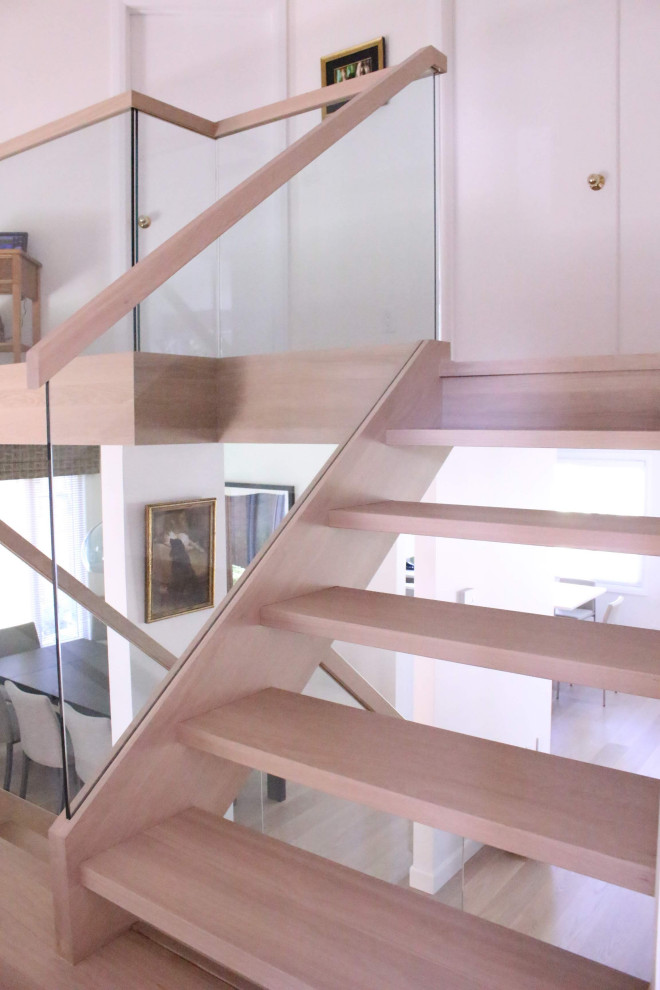 Aménagement d'un escalier moderne avec des marches en bois, des contremarches en bois et un garde-corps en verre.