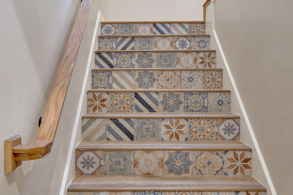 Diseño de escalera en L mediterránea grande con escalones de madera, contrahuellas con baldosas y/o azulejos y barandilla de madera