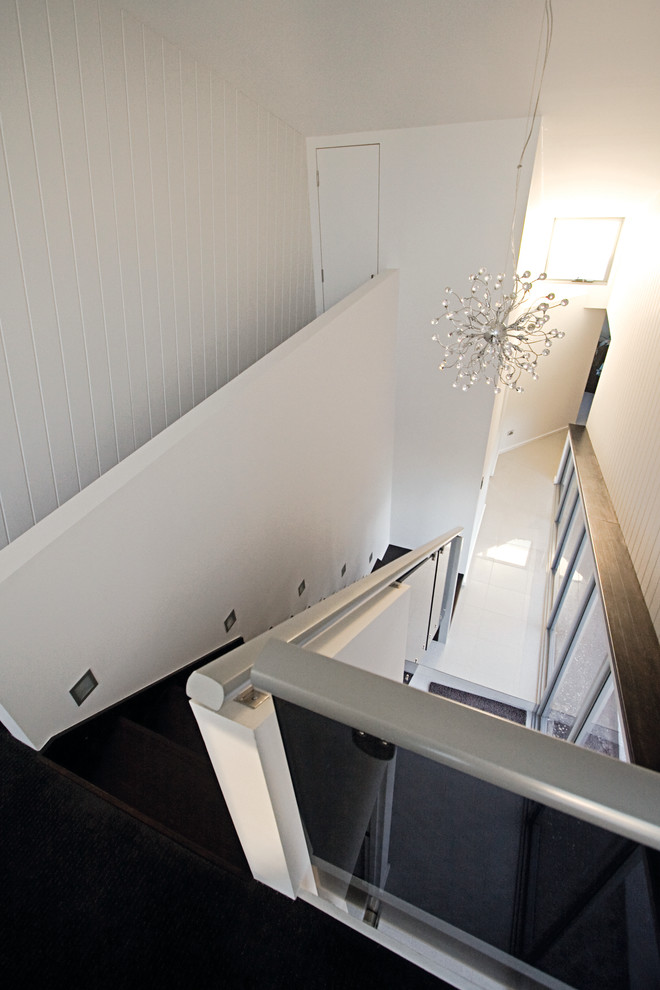 На фото: лестница в стиле лофт с ступенями с ковровым покрытием и ковровыми подступенками с