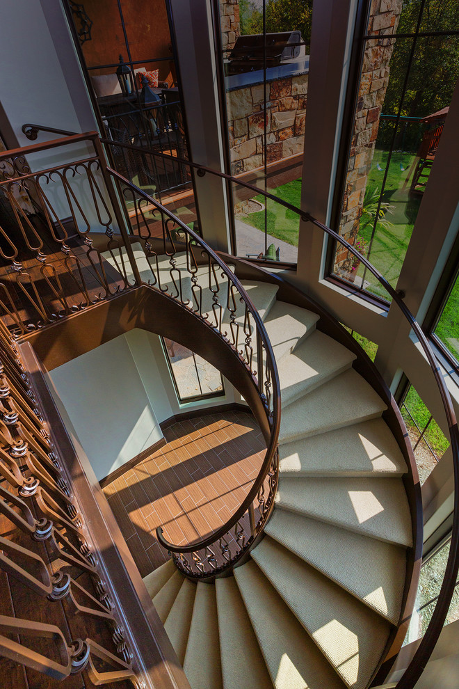 На фото: большая винтовая лестница в классическом стиле с ступенями с ковровым покрытием и ковровыми подступенками