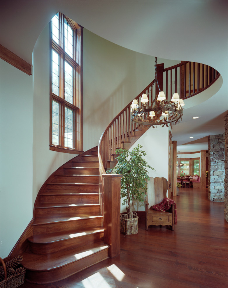 This is an example of a large classic curved wood railing staircase in Atlanta.