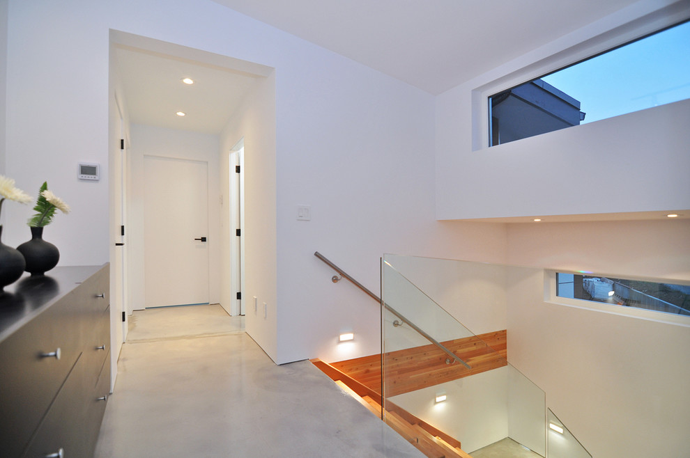 Cette photo montre un grand escalier sans contremarche moderne en U avec des marches en bois et un garde-corps en verre.