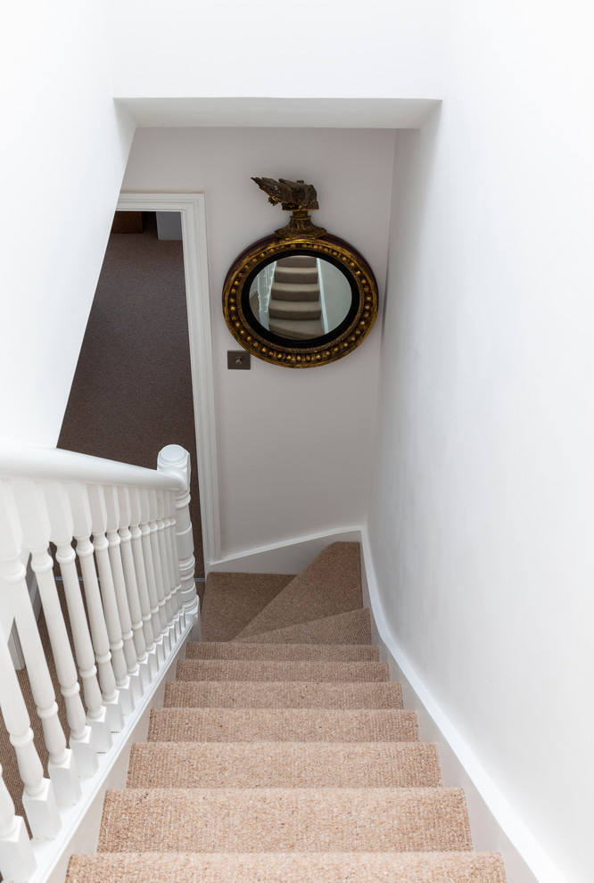 This is an example of a medium sized traditional carpeted straight wood railing staircase in London with carpeted risers.