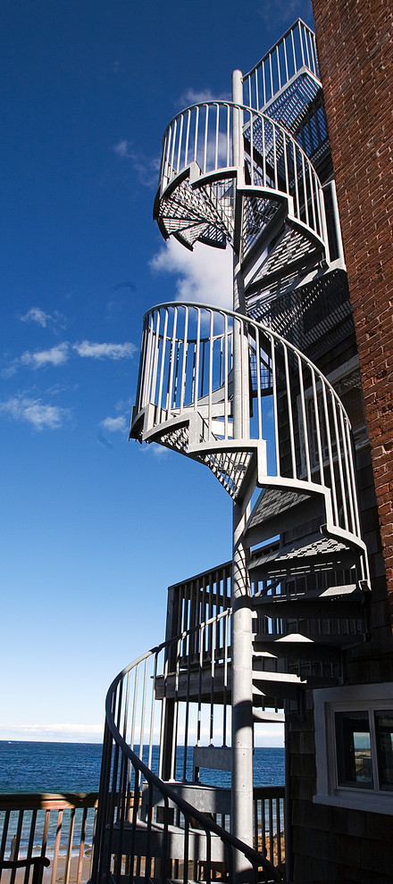 Foto de escalera de caracol industrial de tamaño medio con escalones de metal, contrahuellas de metal y barandilla de metal