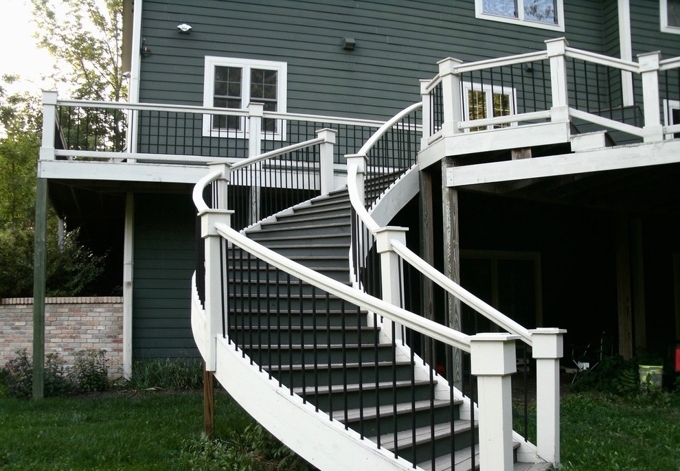 Imagen de escalera curva campestre grande con escalones de madera, contrahuellas de metal y barandilla de madera