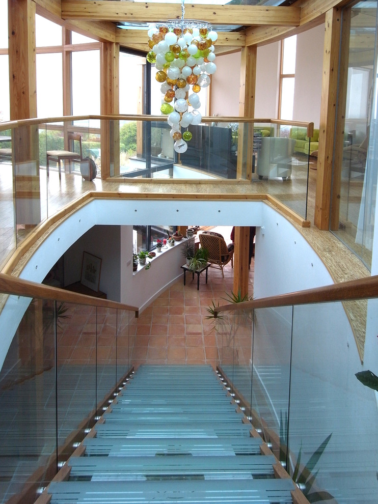 Aménagement d'un escalier droit contemporain de taille moyenne avec des marches en verre, des contremarches en métal et un garde-corps en bois.