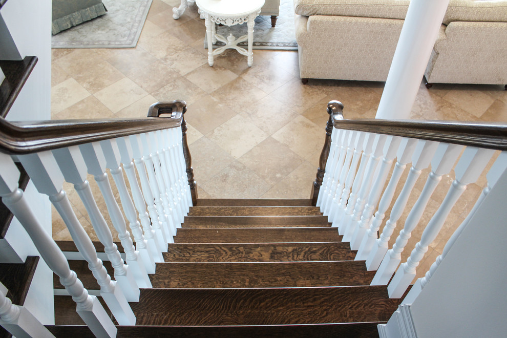 Cette image montre un grand escalier style shabby chic en U avec des marches en bois et des contremarches en bois.