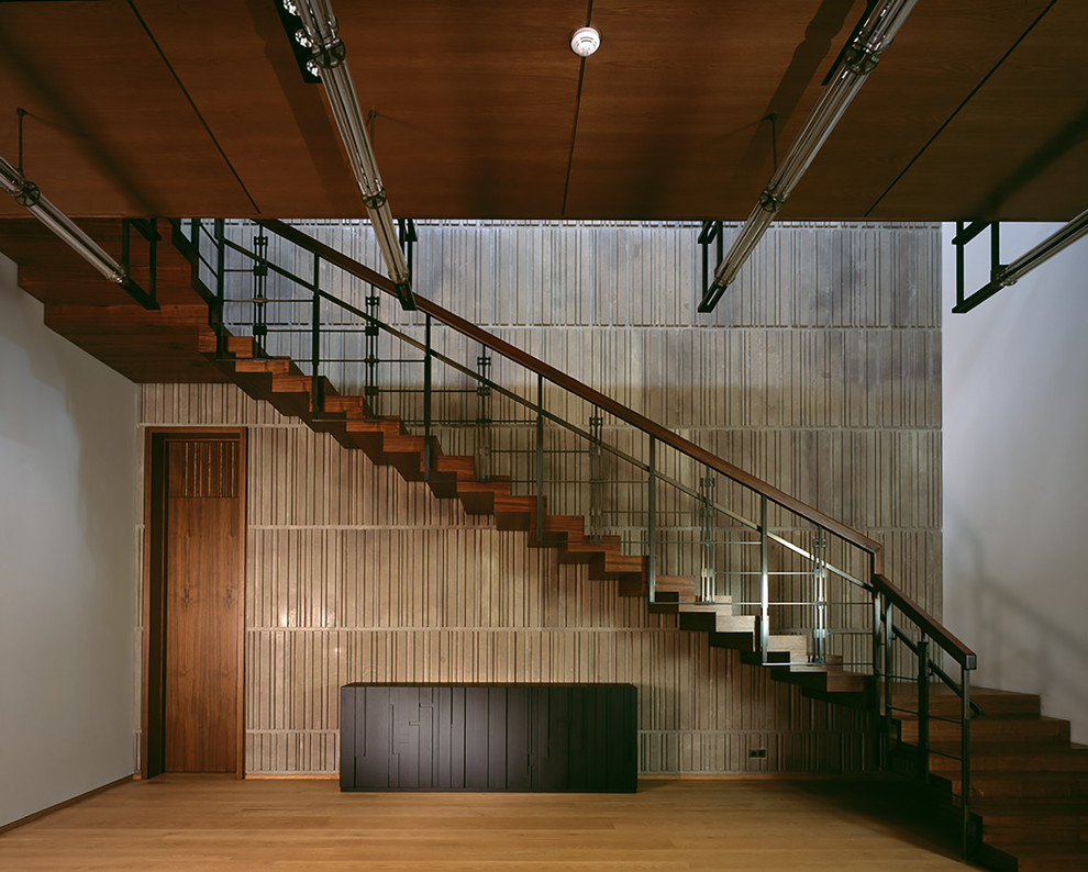 Cette photo montre un grand escalier industriel en U avec des marches en bois, des contremarches en bois et un garde-corps en métal.