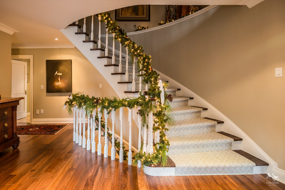 Photo of a large classic wood curved staircase in Toronto with painted wood risers.