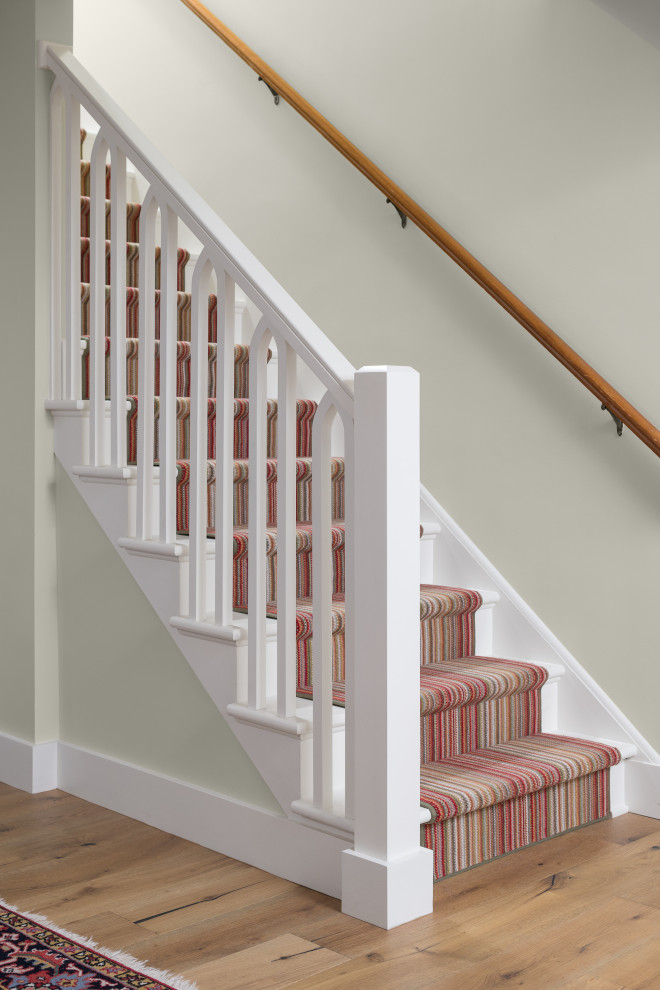 На фото: прямая деревянная лестница в современном стиле с ступенями с ковровым покрытием и деревянными перилами с