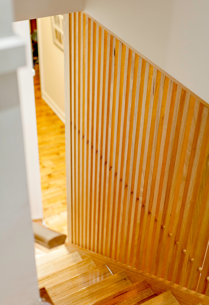 Ejemplo de escalera en L actual con escalones de madera y contrahuellas de madera