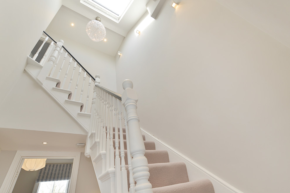 Medium sized classic wood curved wood railing staircase in London with carpeted risers.