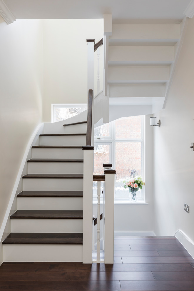 Idée de décoration pour un escalier courbe tradition de taille moyenne avec des marches en bois, des contremarches en bois et un garde-corps en bois.