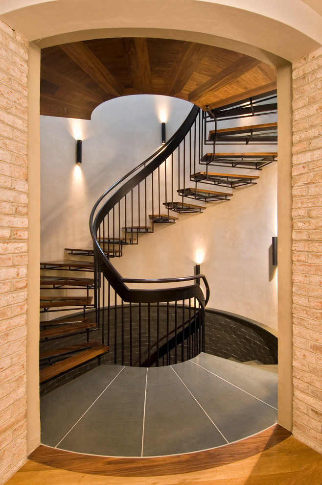 Aménagement d'un grand escalier sans contremarche hélicoïdal classique avec un garde-corps en métal et des marches en bois.