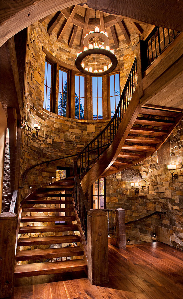 Cette image montre un escalier sans contremarche courbe chalet avec des marches en bois, un garde-corps en métal et palier.