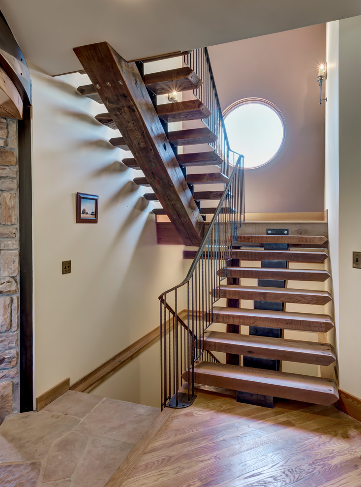 Diseño de escalera en U de estilo de casa de campo grande sin contrahuella con escalones de madera y barandilla de metal