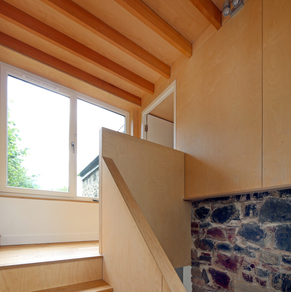 На фото: прямая деревянная лестница среднего размера в современном стиле с деревянными ступенями, деревянными перилами и панелями на части стены