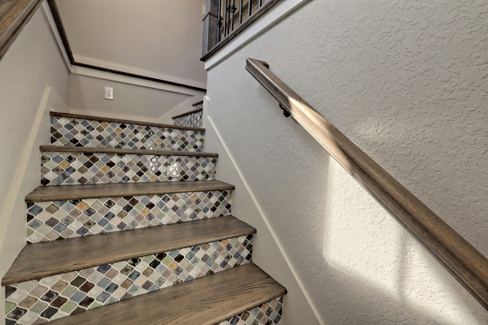 Foto de escalera en L de estilo americano de tamaño medio con escalones de madera, contrahuellas con baldosas y/o azulejos y barandilla de madera